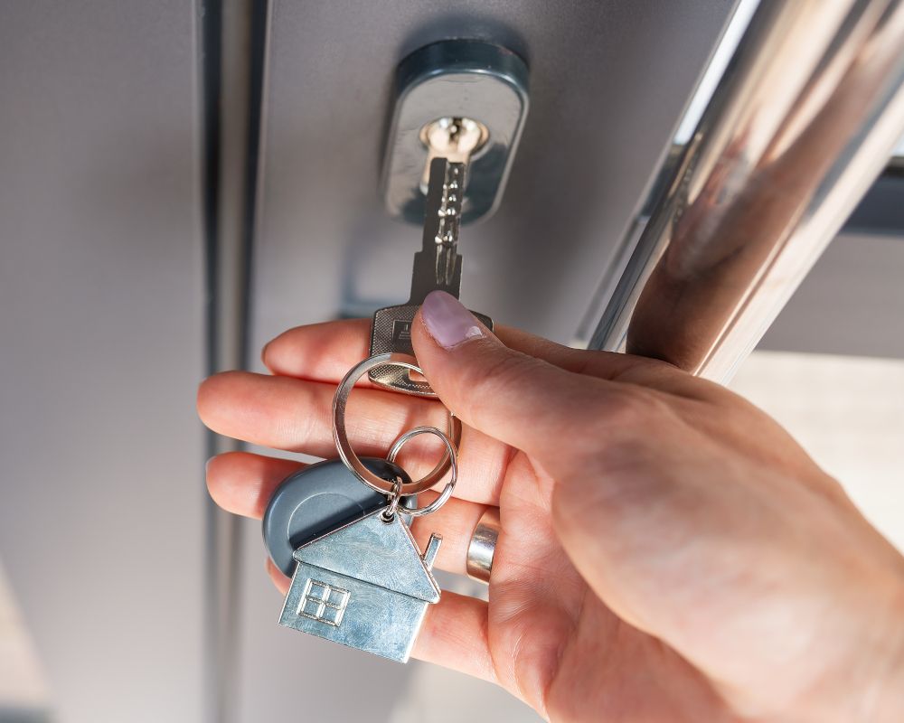 La mano de una mujer que está metiendo la llave en la cerradura para abrir la puerta.